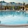 a pool with a deck and chairs by it and a building in the background